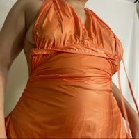 a woman is posing in an orange dress