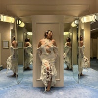 a woman in a white dress standing in front of mirrors