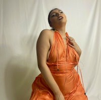 a woman in an orange dress posing on a white background